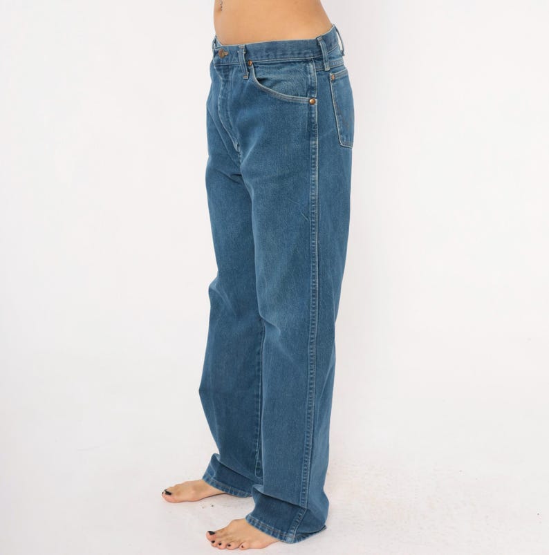 May include: Blue denim jeans with a classic five-pocket design. The jeans have a straight leg cut and a medium wash. The image shows the jeans from the side, highlighting the fit and details of the garment.
