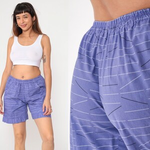 Peut inclure: Shorts bleus avec un motif linéaire blanc et noir. Les shorts ont une taille élastique et des poches. Les shorts sont au genou et fabriqués dans un tissu léger.