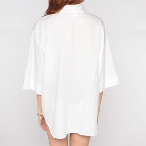 May include: A white, oversized button-down shirt with a collar and short sleeves.