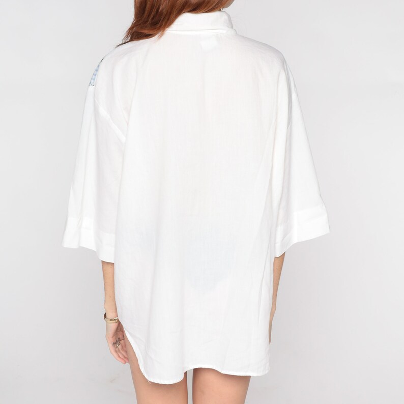 May include: A white, oversized button-down shirt with a collar and short sleeves.