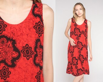 May include: A red sleeveless maxi dress with a black floral print. The dress has a scoop neck and a relaxed fit.