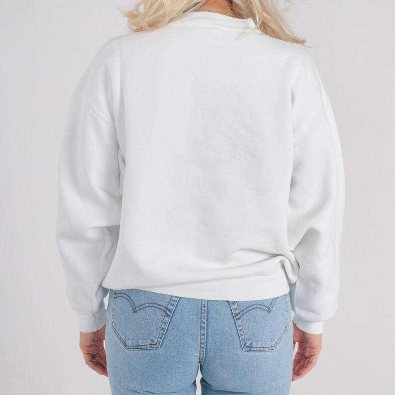 May include: A white crew neck sweatshirt with long sleeves. The sweatshirt is made of a soft, comfortable fabric and has a relaxed fit.