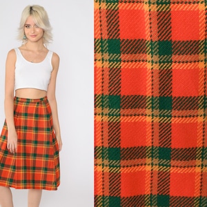 May include: A red, orange, and green plaid midi skirt. The skirt has a pleated design and is made of a soft, comfortable fabric.