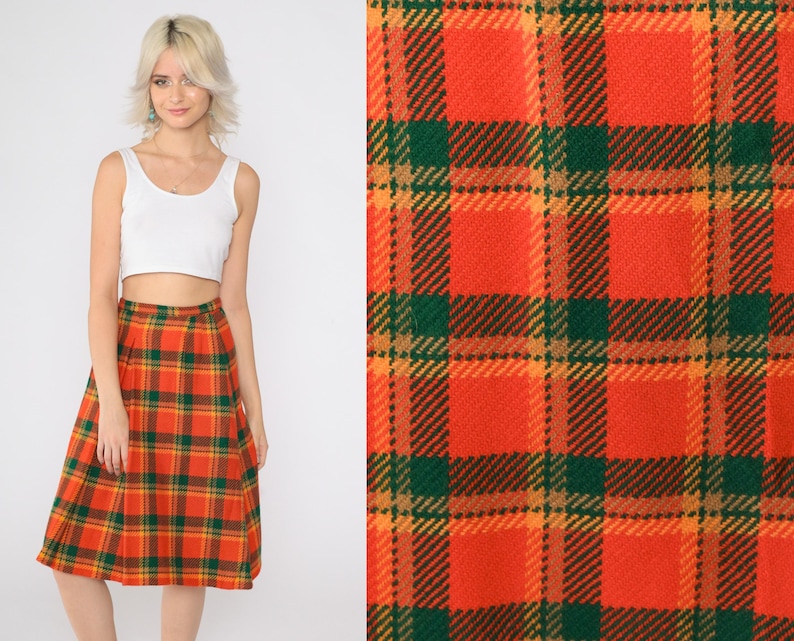 May include: A red, orange, and green plaid midi skirt. The skirt has a pleated design and is made of a soft, comfortable fabric.
