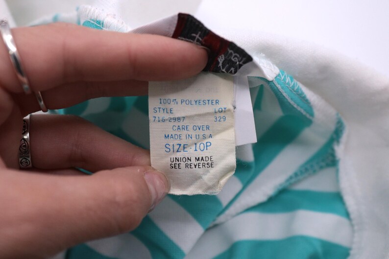 May include: White and turquoise striped shirt with a white tag that reads "100% Polyester", "Style 716-2987", "Lot 329", "Care Over", "Made in USA", "Size 10P", "Union Made See Reverse".