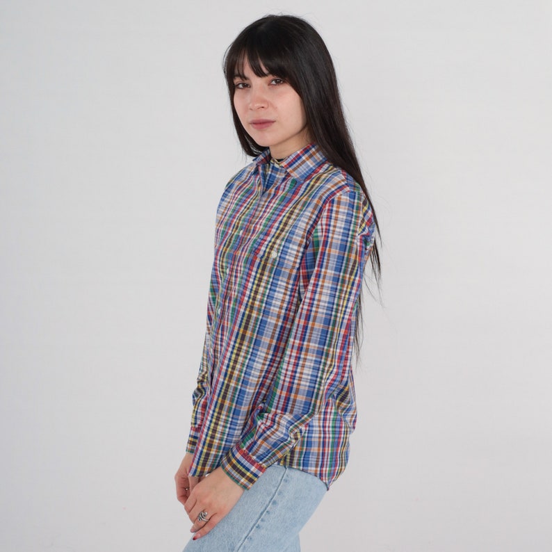 Pode incluir: Uma camisa de xadrez de manga comprida com um esquema de cores azul, vermelho, verde e marrom. A camisa tem um colarinho abotoado e um caimento relaxado.