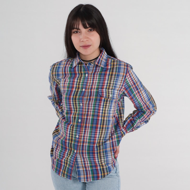 Pode incluir: Uma camisa de manga comprida xadrez com colarinho de bot&otilde;es. A camisa tem um padr&atilde;o xadrez multicolorido com tons azuis, vermelhos, verdes e amarelos.