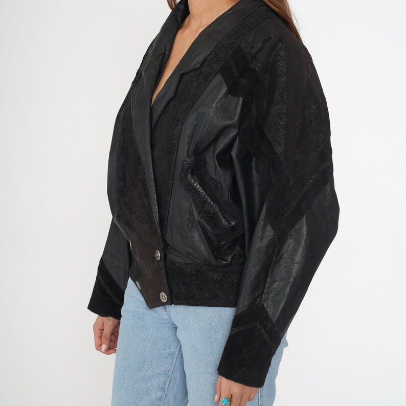 May include: A black leather jacket with suede accents. The jacket has a double-breasted closure and a collar.