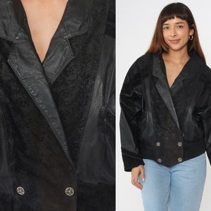 May include: A black leather jacket with a double-breasted closure and a textured pattern. The jacket has a collar and long sleeves.