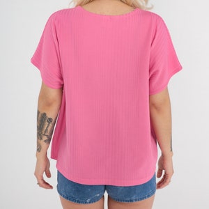 May include: A pink ribbed short-sleeved top with a scoop neck.