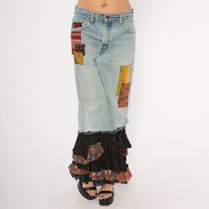 May include: Light blue denim skirt with patchwork details and a tiered black ruffle hem. The skirt features colourful fabric patches in red, yellow, and patterned designs. The skirt is a maxi length.