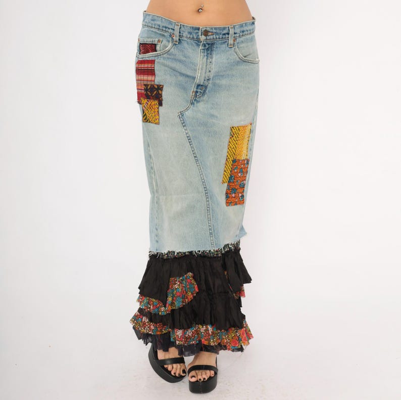 May include: Light blue denim skirt with patchwork details and a tiered black ruffle hem. The skirt features colourful fabric patches in red, yellow, and patterned designs. The skirt is a maxi length.