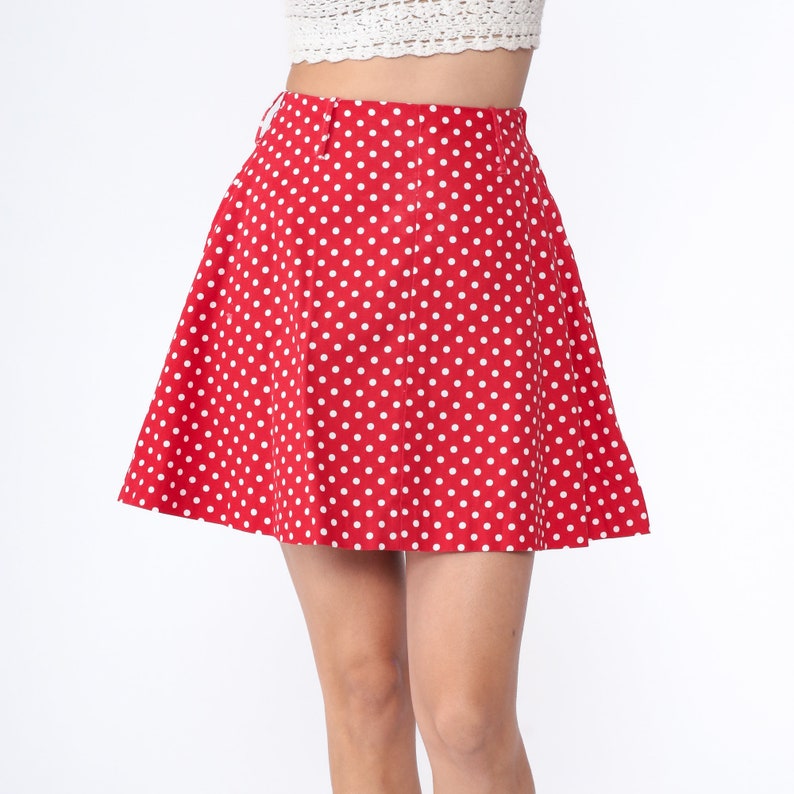 Peut inclure: Une jupe rouge &agrave; pois blancs. La jupe est trap&egrave;ze et a une taille haute.