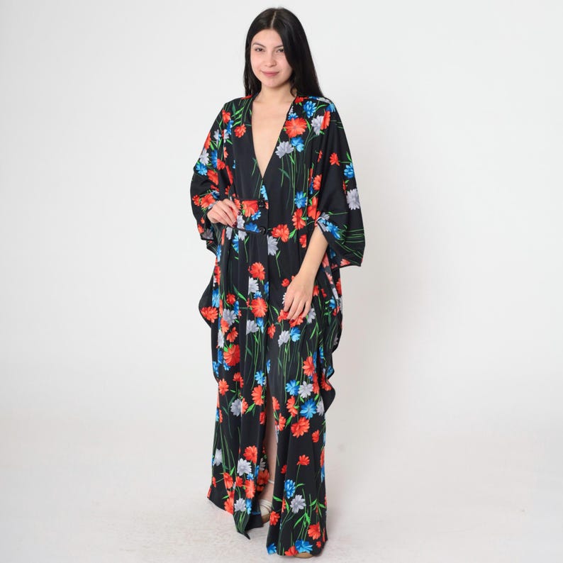 May include: A black maxi dress with a floral print featuring red, blue, and white flowers. The dress has a V-neckline and long sleeves.