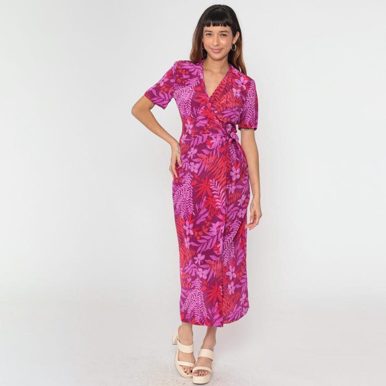 May include: A pink and red floral print wrap dress with short sleeves. The dress has a V-neckline and a tie waist.