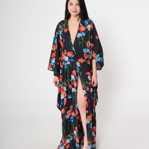 May include: A long black maxi dress with a floral print in shades of red, blue, and white. The dress has a deep V-neckline, a front slit, and long sleeves.