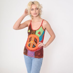 May include: A brown tank top with a patchwork design featuring a peace sign, hearts, and other colorful embroidery.