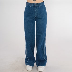 May include: A pair of high-waisted, wide-leg jeans in a dark blue wash. The jeans have a straight leg and a slightly flared hem.
