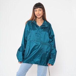 Puede incluir: Chaqueta cortavientos de nylon azul turquesa con cierre de botones a presión y bolsillo canguro. La chaqueta tiene capucha con cordón.