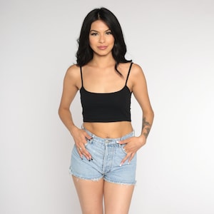 Op de afbeelding: Een vrouw draagt een zwart crop top en een lichtblauwe denim short.