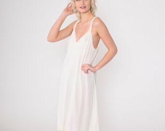 May include: Ivory-colored slip dress with a V-neckline and delicate lace trim along the neckline and hem. The dress features thin straps and a flowing, knee-length design. The fabric appears soft and lightweight, suitable for sleepwear or layering.