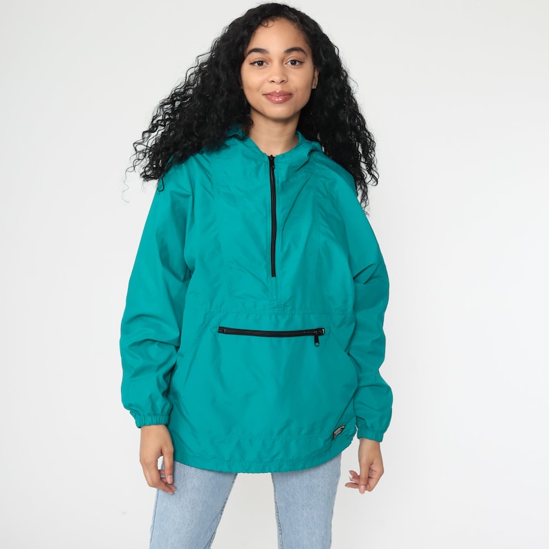 May include: Teal blue hooded jacket with a zipper closure and a kangaroo pocket. The jacket has a black zipper and a black drawstring hood.