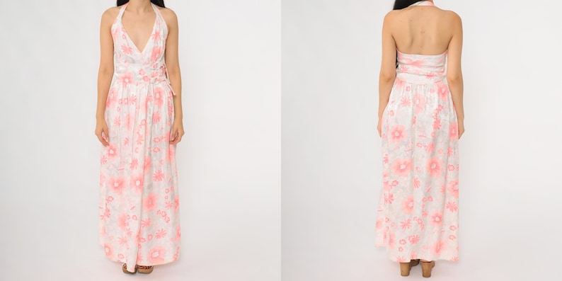 May include: A floor-length halter dress with a floral pattern in shades of pink and white. The dress features a V-neckline and a flowing skirt. The back of the dress is also visible, showcasing the halter tie and the continuation of the floral print.