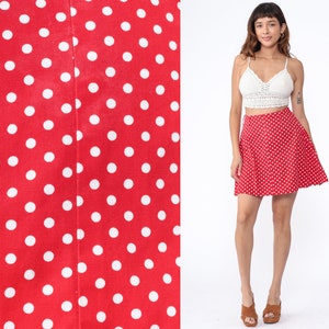 Peut inclure: Une jupe rouge &agrave; pois blancs. La jupe est trap&egrave;ze et a une taille haute.