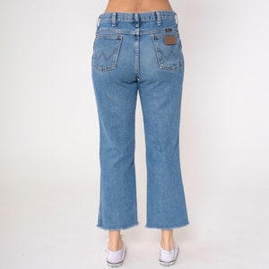 May include: A pair of light blue denim jeans with a frayed hem. The jeans have a high waist and a straight leg.