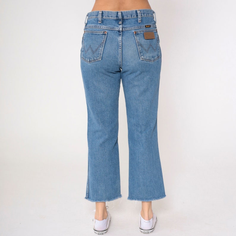 May include: A pair of light blue denim jeans with a frayed hem. The jeans have a high waist and a straight leg.