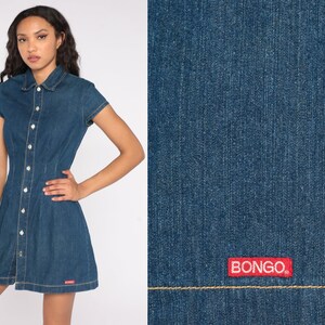 May include: A short-sleeved denim dress with a button-up front, collar, and a-line skirt. The dress is a medium blue wash with white buttons and the brand name "BONGO" in red on the lower right side.