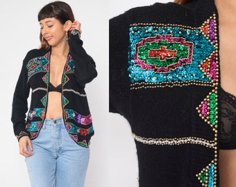 May include: Black cardigan with colorful sequin and bead embroidery. The cardigan has a long sleeve and open front design.