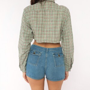Puede incluir: Una camisa corta de manga larga con un patr&oacute;n de cuadros en verde claro y rojo, combinada con pantalones cortos de mezclilla azul que incluyen dos bolsillos traseros con solapas abotonadas. La camisa tiene cuello y pu&ntilde;os abotonados.
