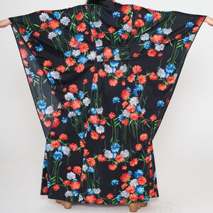 May include: A black maxi dress with a floral print featuring red, blue, and white flowers. The dress has a wide, flowing silhouette and a long, flowing skirt.