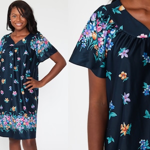 May include: A navy blue dress with a V-neck and short sleeves. The dress is adorned with a colorful floral pattern, featuring pink, blue, yellow, and orange flowers. The floral design is concentrated on the sleeves and the hemline.