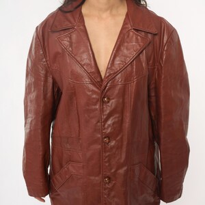 May include: A brown leather jacket with a classic design. The jacket features a notched collar, three buttons, and two front pockets. The leather has a slightly worn appearance.