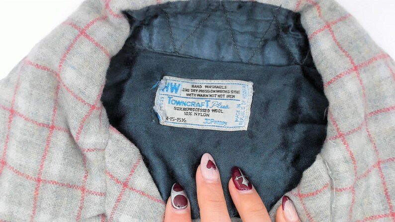 Puede incluir: Una camisa gris con un patr&oacute;n de cuadr&iacute;cula roja y un forro interior acolchado de color azul oscuro. Una etiqueta rectangular blanca est&aacute; cosida en el &aacute;rea del cuello, con el texto Towncraft Plus, 90% lana reprocesada, 10% nailon.
