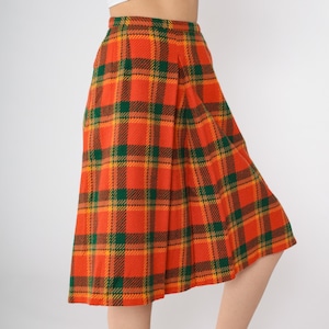 May include: A pleated skirt with a plaid pattern in orange, green, and yellow.