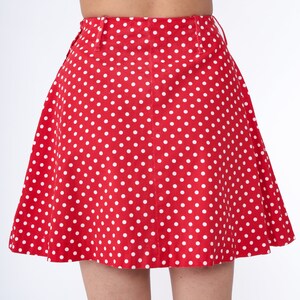 Peut inclure: Une jupe rouge &agrave; pois blancs. La jupe est trap&egrave;ze et a une taille haute.