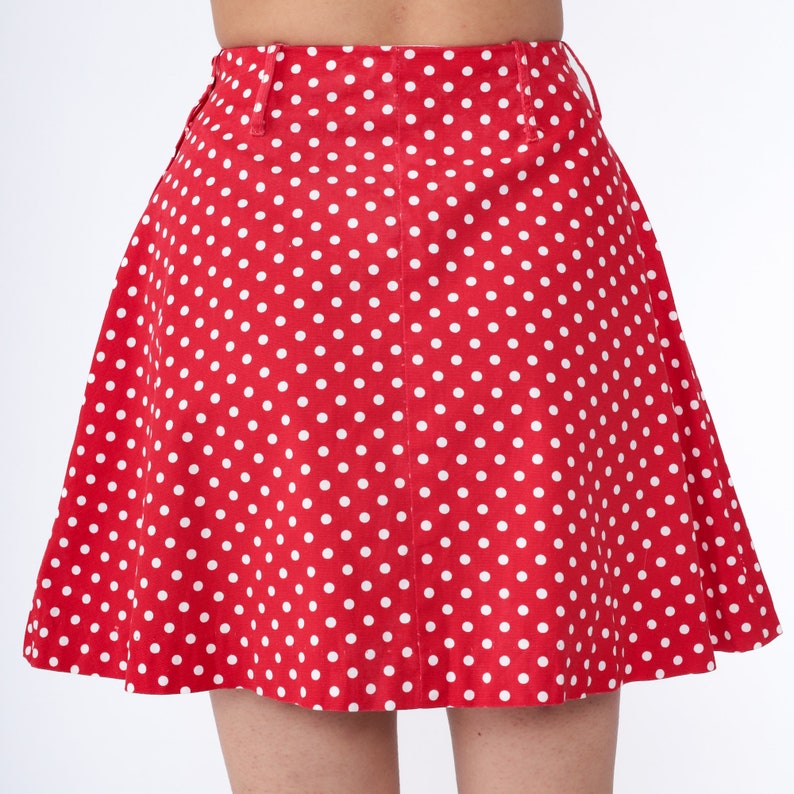 Peut inclure: Une jupe rouge &agrave; pois blancs. La jupe est trap&egrave;ze et a une taille haute.