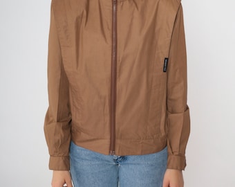 May include: A brown zip-up jacket with a stand-up collar and long sleeves. The jacket has a small black label on the left side with the text "AMERICAN  CLUB".