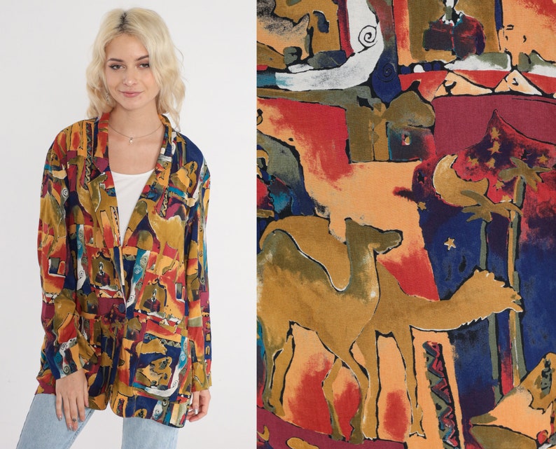May include: A colorful, open-front blazer with a vibrant abstract pattern in shades of yellow, red, blue, and brown. The blazer features a classic lapel and two front pockets. The fabric design includes camel figures and architectural shapes.