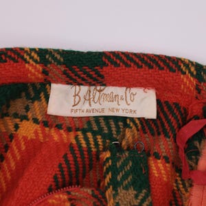 May include: A red, green, and yellow plaid fabric with a white label that reads "B. Altman & Co. Fifth Avenue New York".