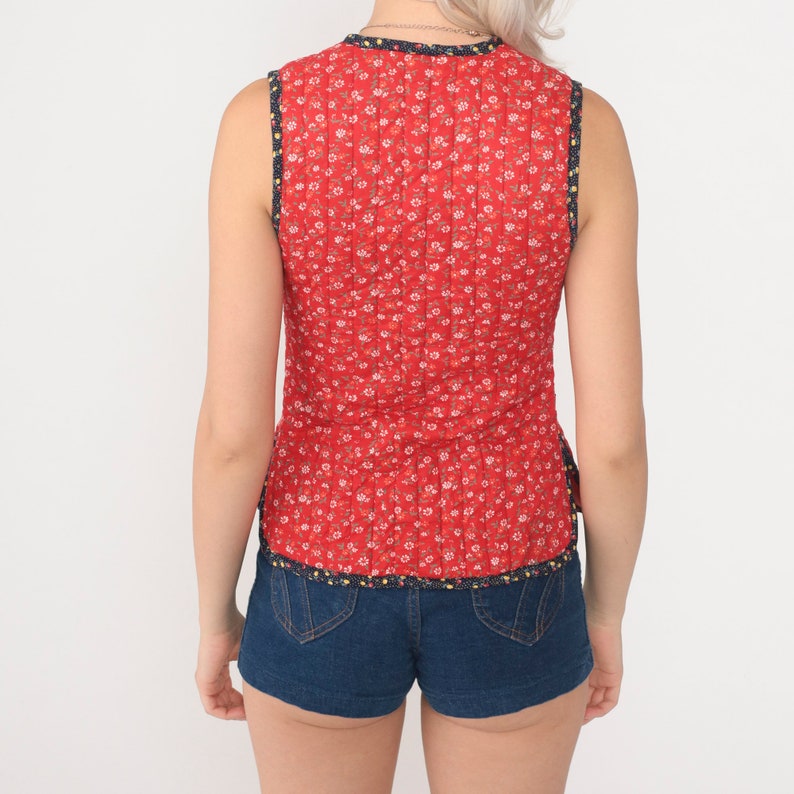 Puede incluir: Top rojo sin mangas con estampado floral y ribete azul. El top est&aacute; acolchado y tiene una silueta ajustada. La modelo lleva pantalones cortos de mezclilla azul.