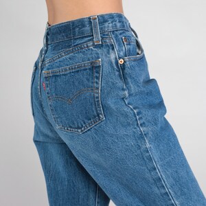 May include: A pair of blue denim jeans with a back pocket and a red tab.