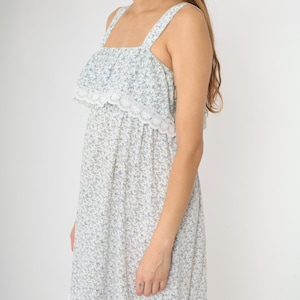 May include: A white sleeveless dress with a blue floral print and a white lace trim around the neckline.