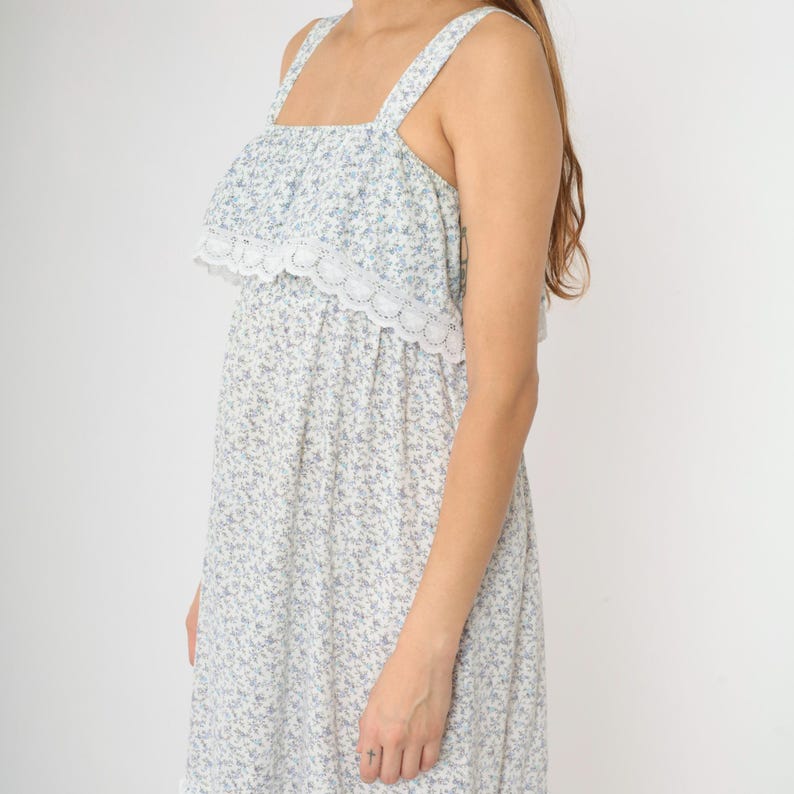 May include: A white sleeveless dress with a blue floral print and a white lace trim around the neckline.