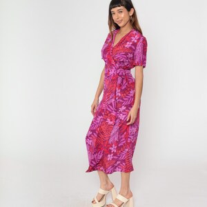 May include: A pink and red floral print wrap dress with short sleeves and a tie waist. The dress is midi length and has a relaxed fit.