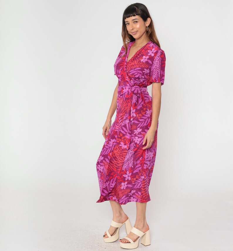 May include: A pink and red floral print wrap dress with short sleeves and a tie waist. The dress is midi length and has a relaxed fit.