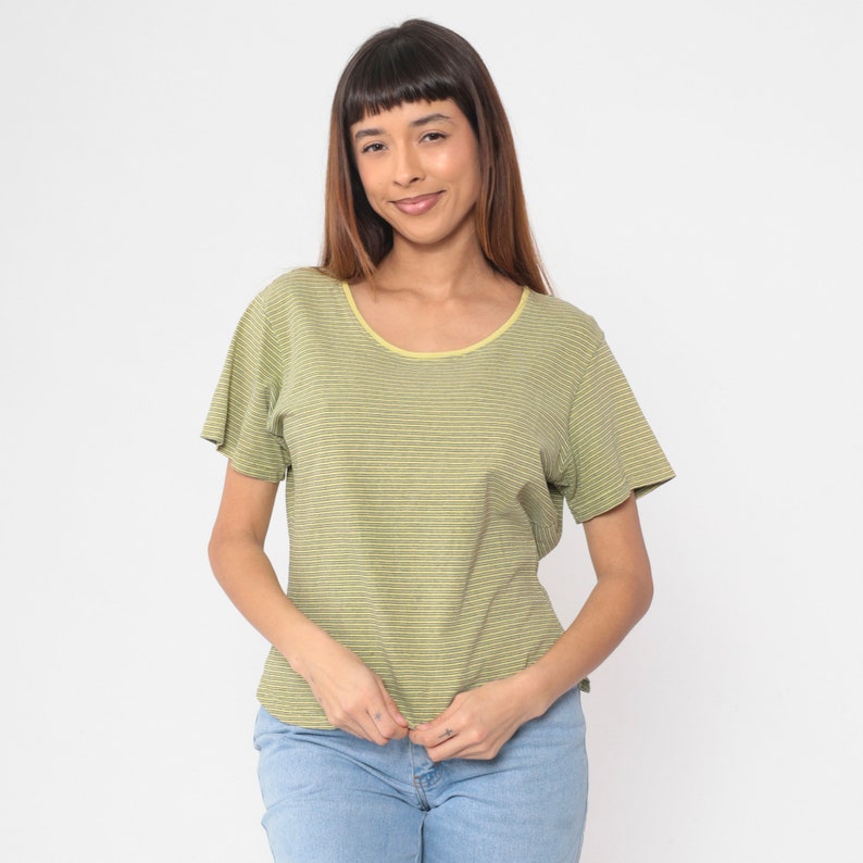 Peut inclure: Un t-shirt &agrave; rayures vertes et blanches avec une encolure jaune. Le t-shirt &agrave; manches courtes est fait d'une mati&egrave;re douce et est associ&eacute; &agrave; un jean bleu. Le t-shirt a une encolure ronde et une coupe d&eacute;contract&eacute;e.